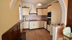 A kitchen with wooden cabinets, a tiled backsplash, and a built-in oven. - In the Peaceful Hillside Village of Aurano (Aurano)