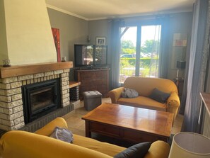 A living room with a fireplace, sofa, coffee table, and a television.