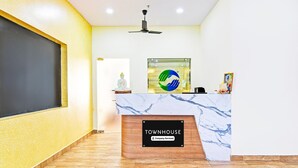 Una recepción con encimera de mármol, ventilador de techo y una estatua en la pared.
