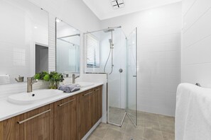 A modern bathroom with a glass shower enclosure, a white sink, and wooden cabinets. - Side by Side New Luxe Homes (Victoria Park)