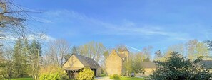 A stone building with a thatched-roof structure, surrounded by trees and greenery.