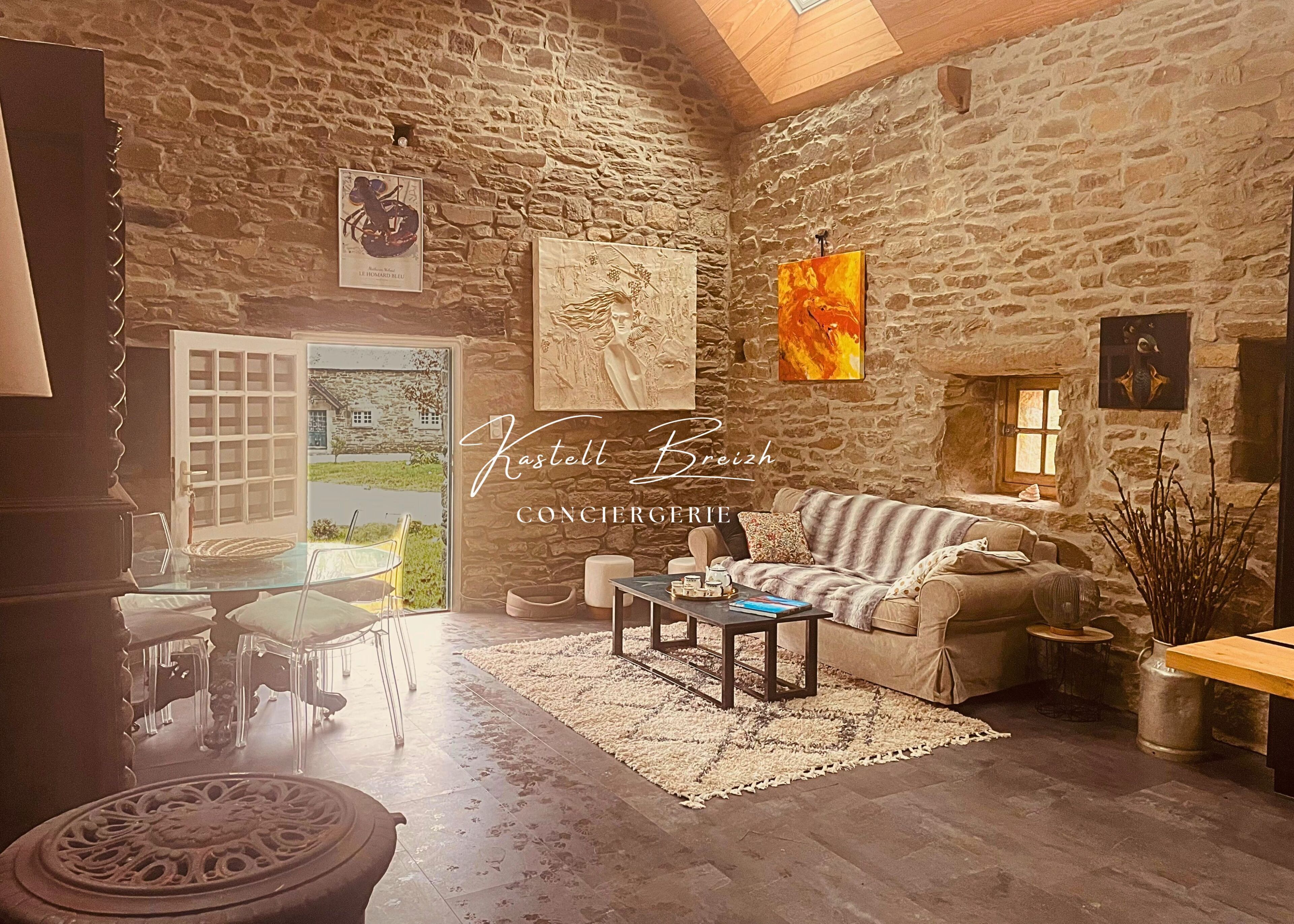 Een rustiek stenen interieur met een gezellige zithoek, een eettafel en kunstwerken aan de muren.