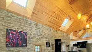 A spacious interior with a stone wall, wooden ceiling, and a modern kitchen area.