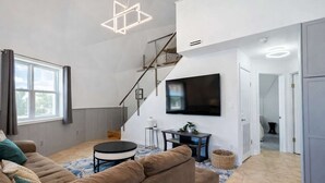 Un saló modern amb una escala, un televisor de pantalla plana i una zona d'estar acollidora.