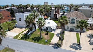 A residential area with a dome-shaped building surrounded by palm trees and a clear view of the ocean. - Unique GeoDome - Half Block to Beach (South Padre Island)