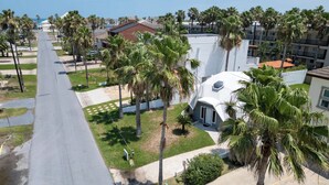Zona residencial amb un edifici de forma de cúpula blanca, palmeres i cel serè.