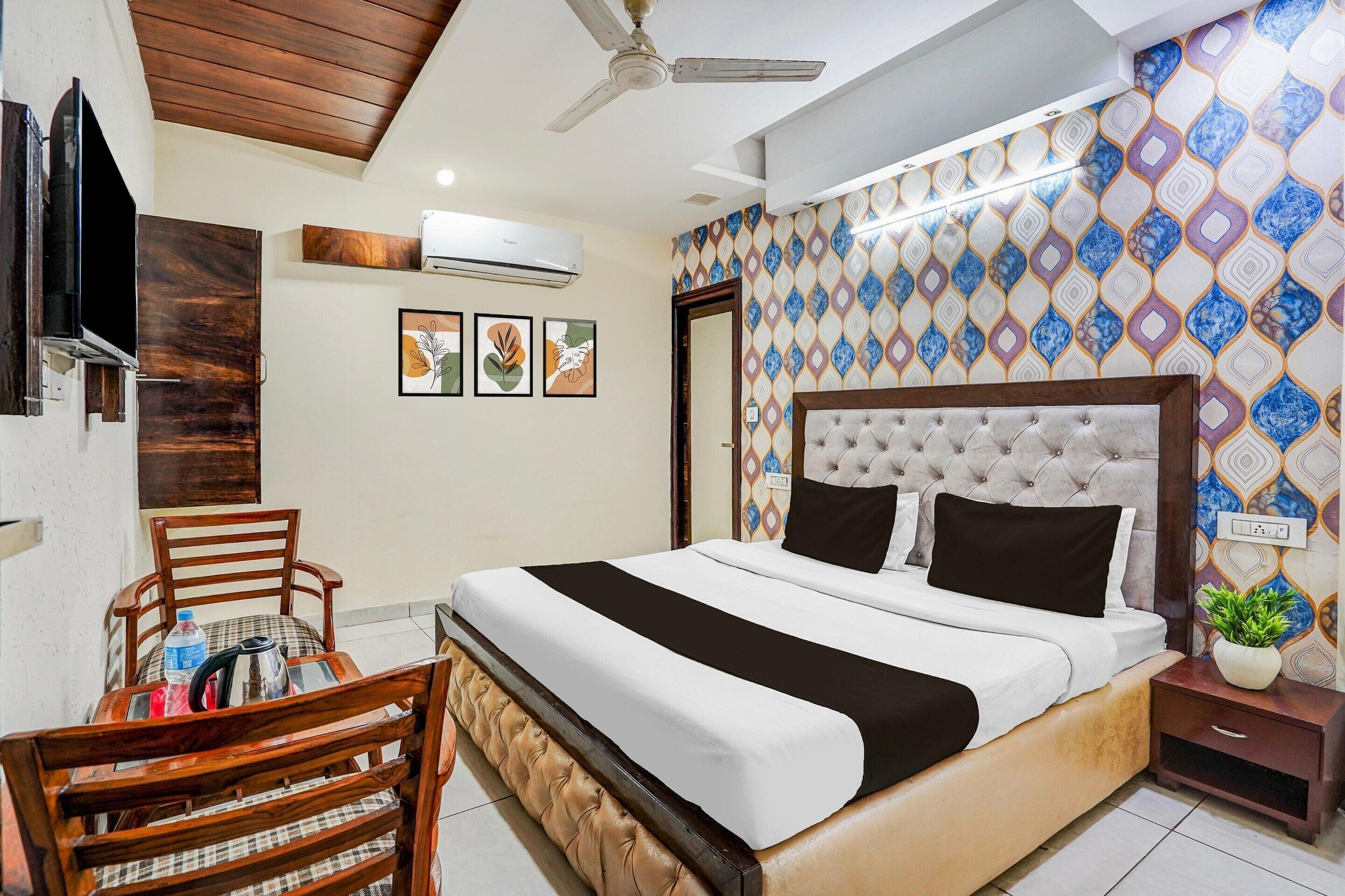A hotel room with a bed, a chair, a table, a TV, and a ceiling fan.