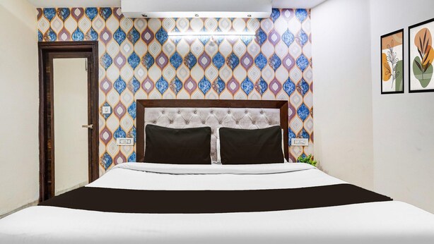 Een hotelkamer met een bed, een behangwand en een deur.