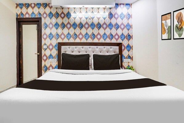 Una habitación de hotel con una cama, un papel tapiz estampado y una puerta.