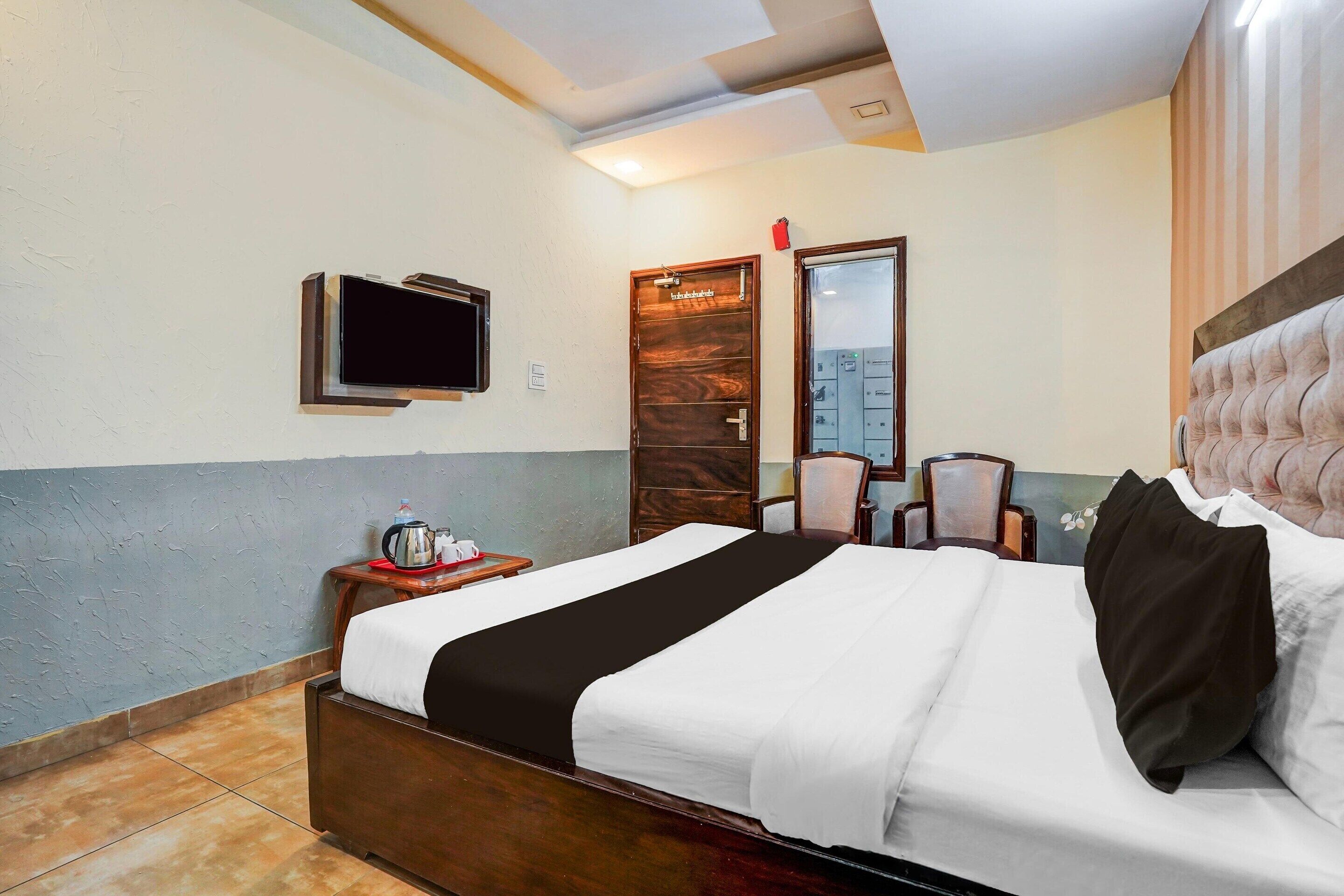 Een hotelkamer met een bed, een aan de muur bevestigde televisie, een houten deur en een stoel.