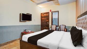 Een hotelkamer met een bed, een aan de muur bevestigde televisie, een houten deur en een stoel.