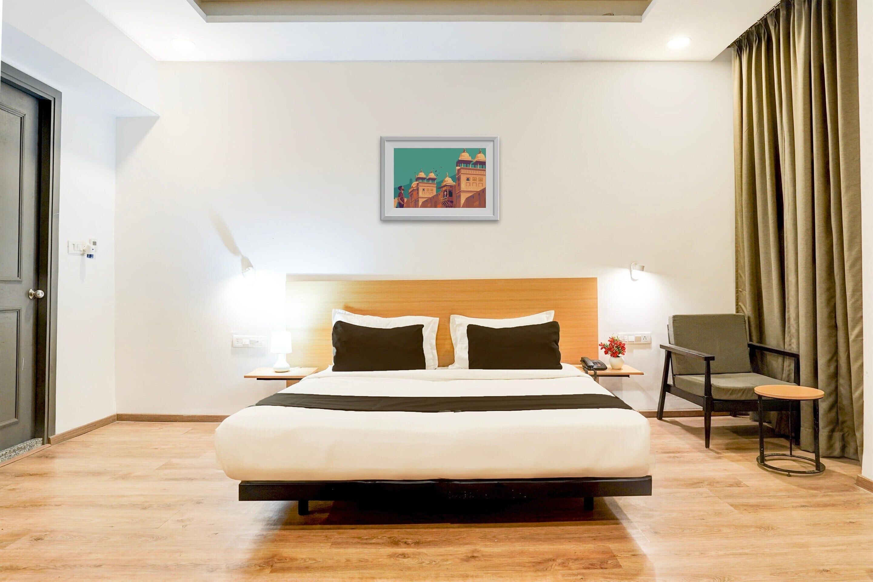 Habitació d'hotel amb llit, taules de nit, una cadira i un quadre a la paret.
