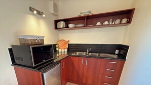 Eine kleine Küche mit Mikrowelle, Kühlschrank, Spüle und Holzschränken.
