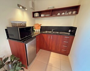 A compact kitchen with a microwave, refrigerator, sink, and wooden cabinets.
