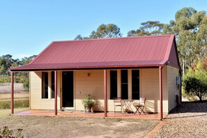 A single-story building with a red roof, a covered porch, and a small outdoor seating area.