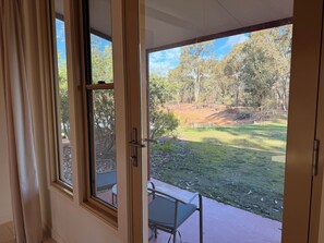 A room with a sliding glass door leading to an outdoor area with a grassy lawn, trees, and a small pond.
