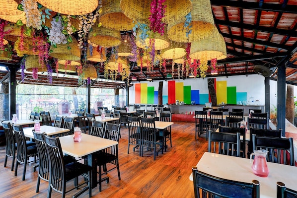 A restaurant with tables and chairs, a colorful wall, and hanging decorations. - Deluxe Townhouse Central Olive Star (Mysore)