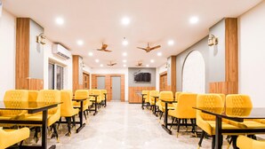 A conference room with yellow chairs, black tables, ceiling fans, and a flat-screen TV mounted on the wall. - Deluxe Pallette Shree Jagannatha Puri Lotus (Puri)