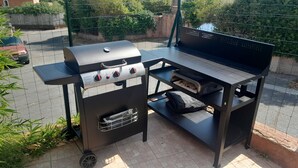 Una parrilla portátil con panel de control, compartimento de almacenamiento y superficie plana para cocinar.