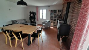 Una sala de estar con una mesa de comedor, sillas, un sofá, una chimenea y una estantería.