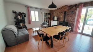 Una sala de estar con un sofá, una mesa de comedor con sillas, una estantería y una chimenea.