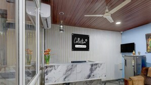A reception desk with a marble top, a ceiling fan, a mounted television, and a sign that reads 'Collection Company-Serviced.' - Super Collection O Forum Mall Hyderabad (Hyderabad)