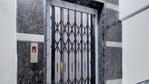 A metal gate with a geometric pattern, a digital display with the number 6, and a handrail on the right. - Super Collection O Forum Mall Hyderabad (Hyderabad)