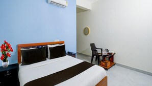 A hotel room with a bed, a desk, a chair, a vase with flowers, and an air conditioner. - Super Collection O Forum Mall Hyderabad (Hyderabad)