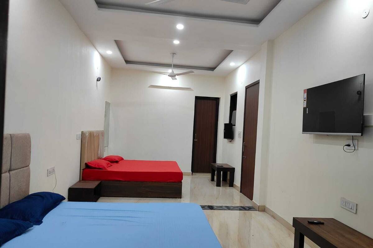 A bedroom with a bed, a TV, a ceiling fan, and a small table.