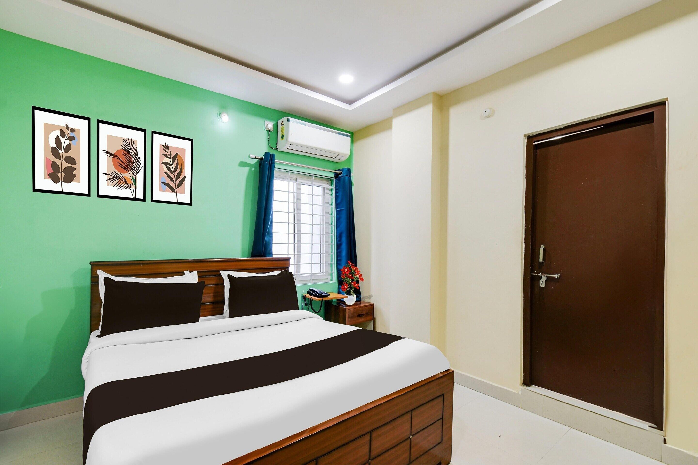 Un dormitorio con cama, ventana con cortinas, aire acondicionado, puerta y cuadros en la pared.