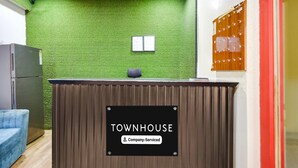 A reception desk with a sign reading 'TOWNHOUSE Company Serviced.' - Deluxe Rks Prestige (Hyderabad)