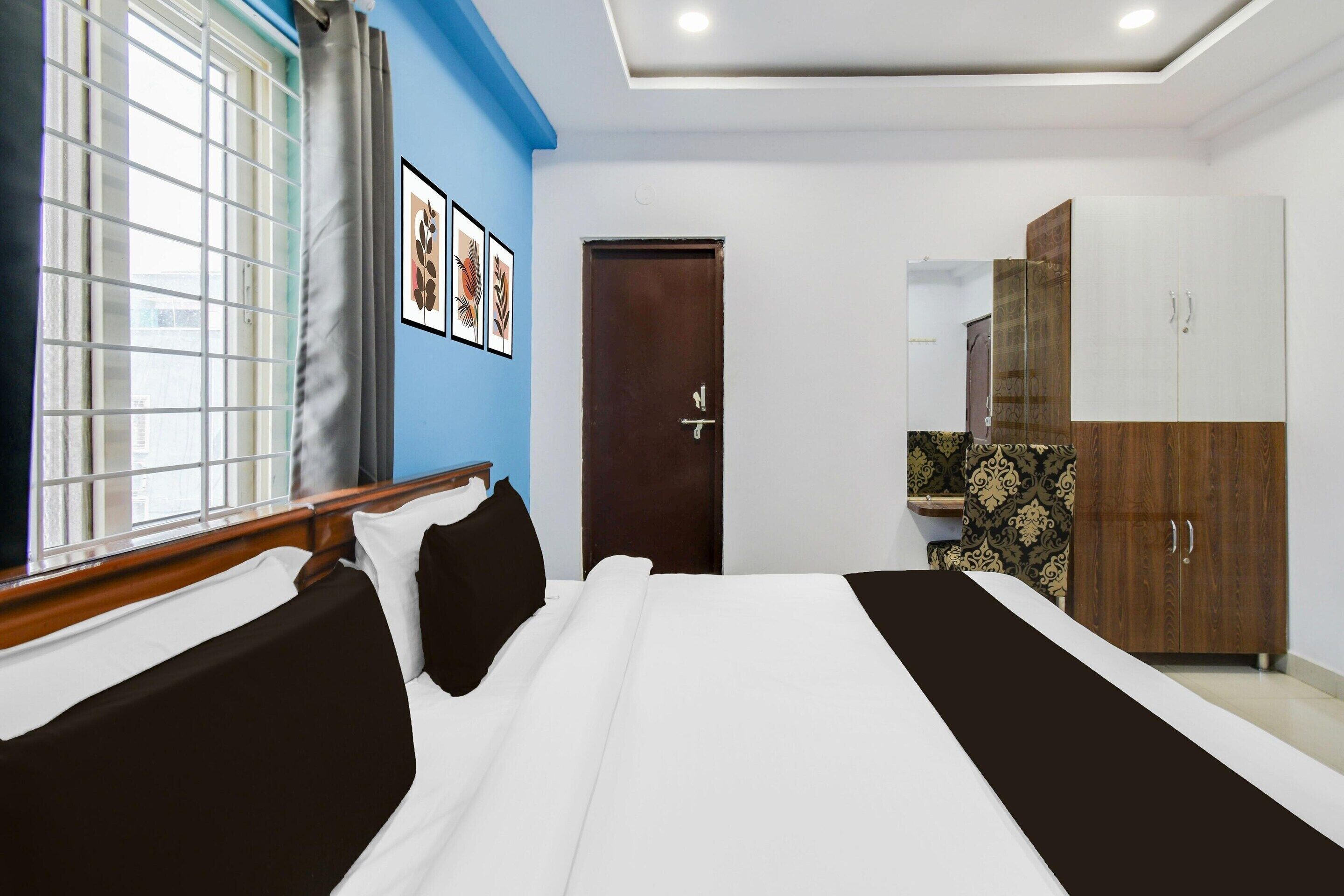 A hotel room with a bed, a wardrobe, a door, and a window with blinds.