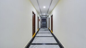 A hallway with doors on both sides, a tiled floor, and a ceiling light. - Deluxe Rks Prestige (Hyderabad)