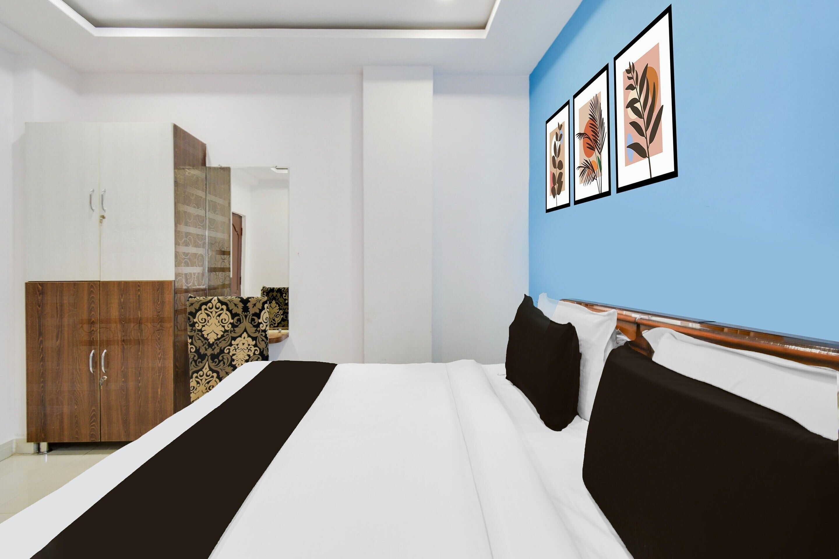 A bedroom with a bed, wardrobe, and framed artwork on the wall.
