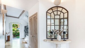 A hallway with a large arched mirror, a stone bench, and a door leading to a staircase. - Sugar Hill Birds Eye Villa - by ZenBreak (Mount Standfast)
