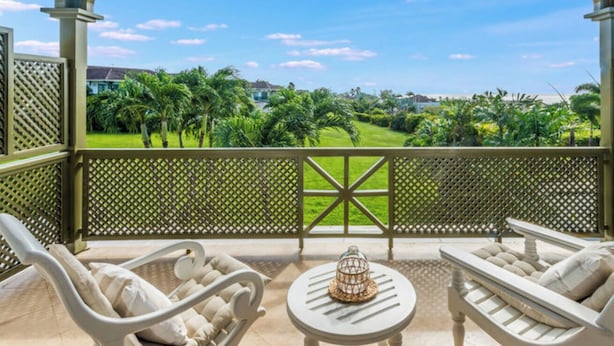 A covered outdoor seating area with a view of a green landscape and palm trees. - Sugar Hill Birds Eye Villa - by ZenBreak (Mount Standfast)