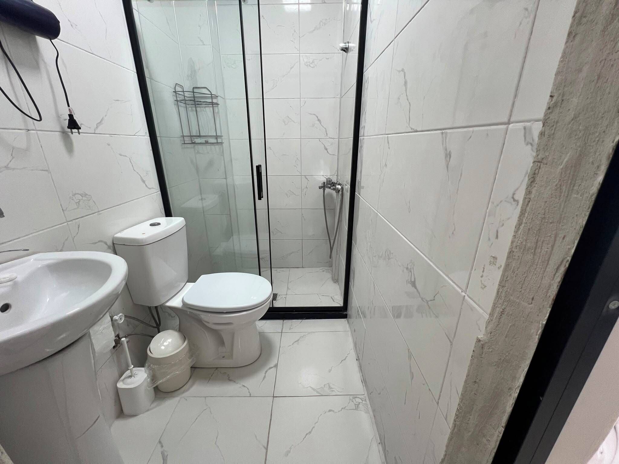 Un baño con inodoro, lavamanos y zona de ducha.