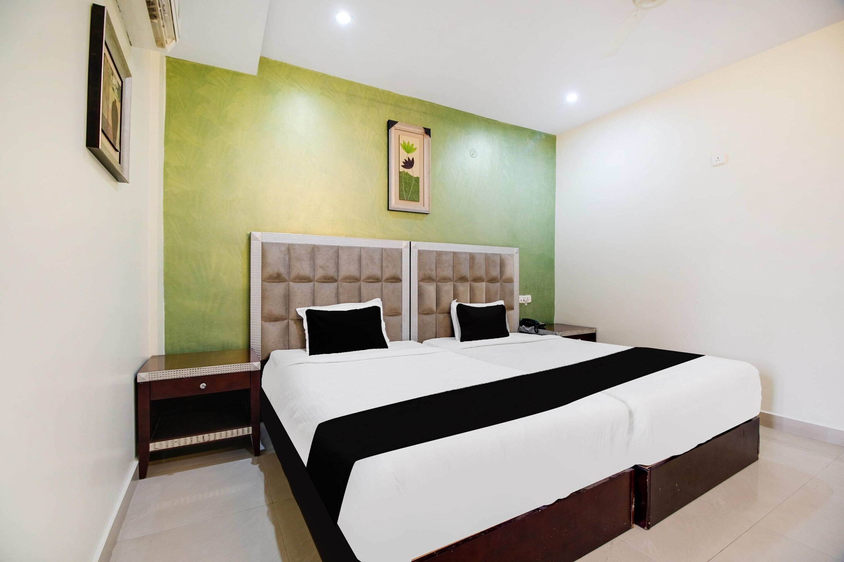 A bedroom with a large bed, two nightstands, a green accent wall, and a framed picture.