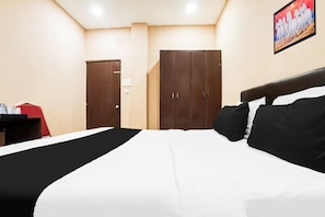 A hotel room with a bed, a wardrobe, and a painting on the wall.