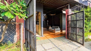 Ein Wohnhaus-Eingangsbereich mit einem Metallgitter, einem Fliesenboden und einer Couch im Inneren.
