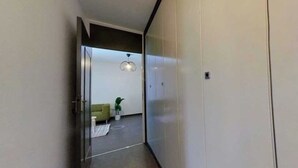 Ein Flur, der zu einem Zimmer mit einer Couch, einem kleinen Tisch und einer Topfpflanze führt.