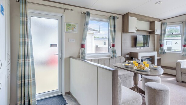 Een caravan keuken met een eethoek, een televisie en uitzicht op de omgeving.
