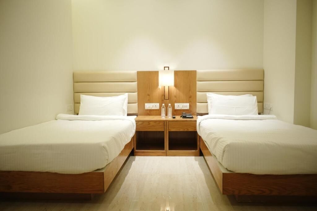 A double room with two beds, wooden headboards, bedside tables, and a wall-mounted light fixture.
