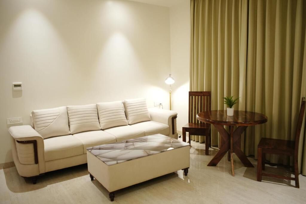 Una sala de estar con un sofá, una mesa de centro, una lámpara, una mesa de comedor y una silla.