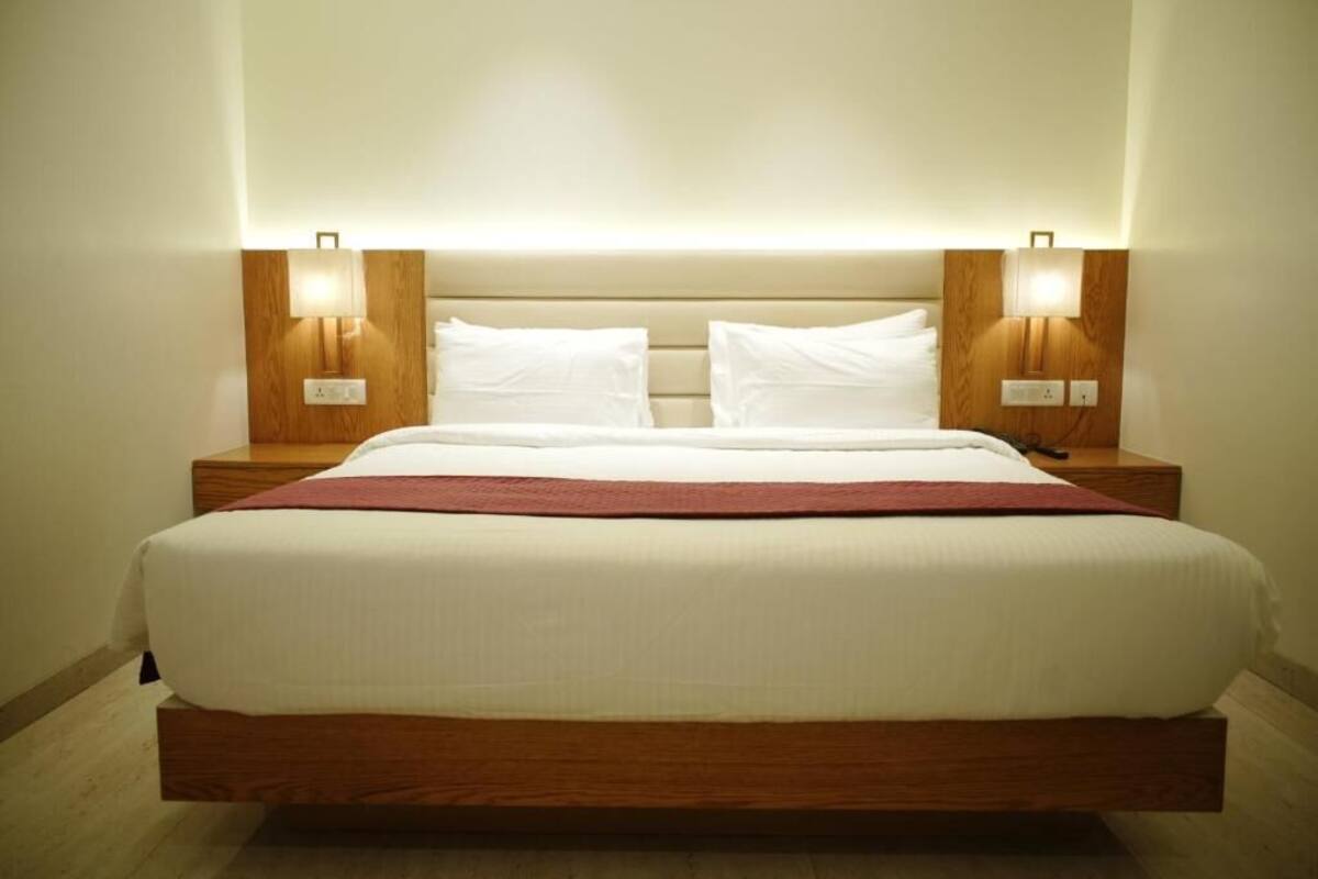 A hotel room with a bed, nightstands, and wall-mounted lamps.