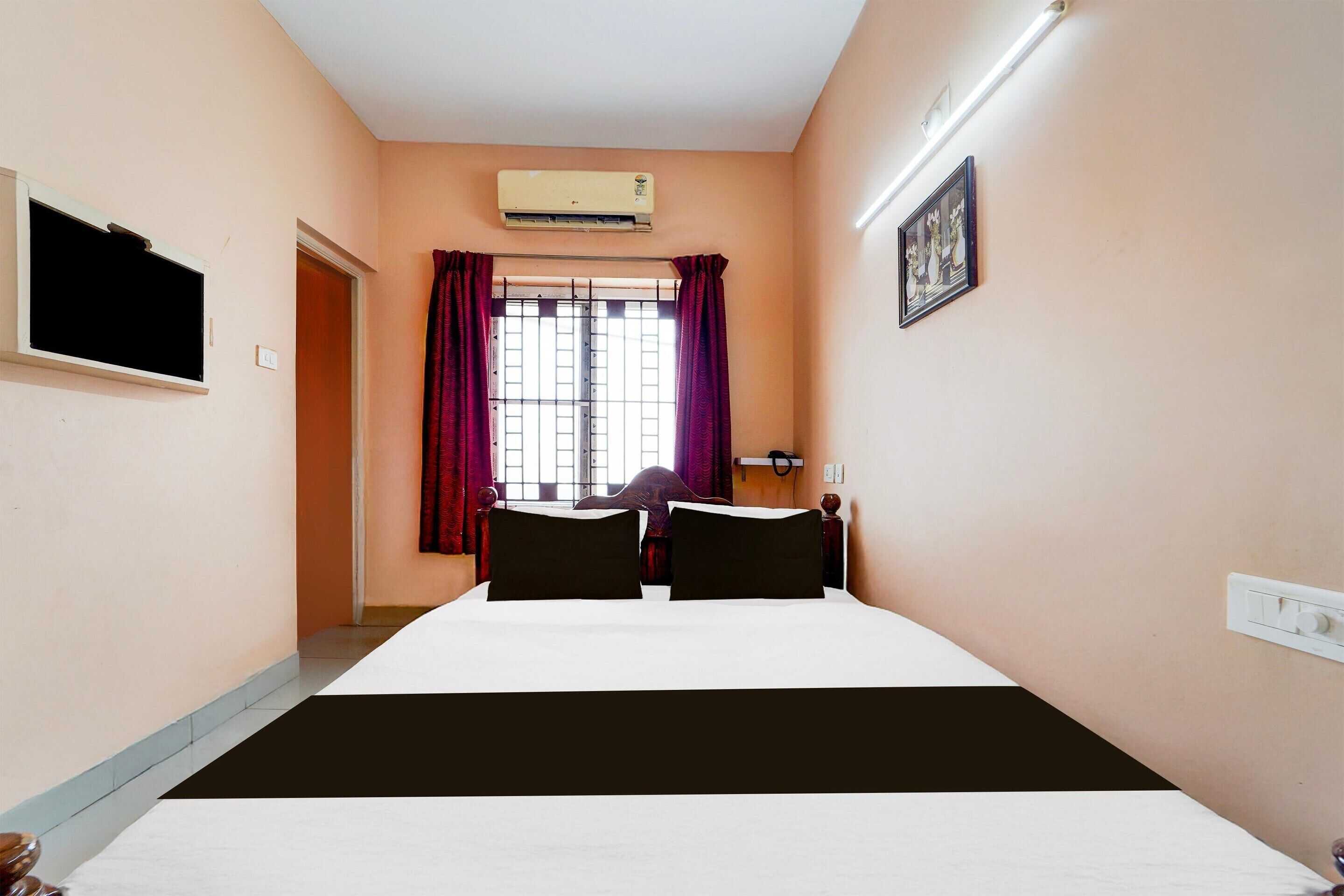 Une chambre d’hôtel équipée d’un lit, d’un appareil de climatisation, d’une télévision et d’une fenêtre avec des rideaux.