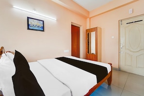 A hotel room with a bed, a door, a mirror, and a painting on the wall. - Super Hotel O Anna Nagar Madurai (Madurai)