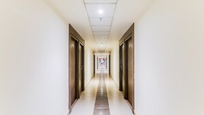 A long, narrow hallway with a tiled floor and wooden doors on both sides. - Deluxe Civil Lines Near Old Bus Stand Imperial (Bareilly)