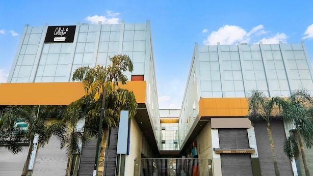 A modern building with a glass facade, a sign reading 'Collection,' and a central entrance with steps. - Deluxe Civil Lines Near Old Bus Stand Imperial (Bareilly)