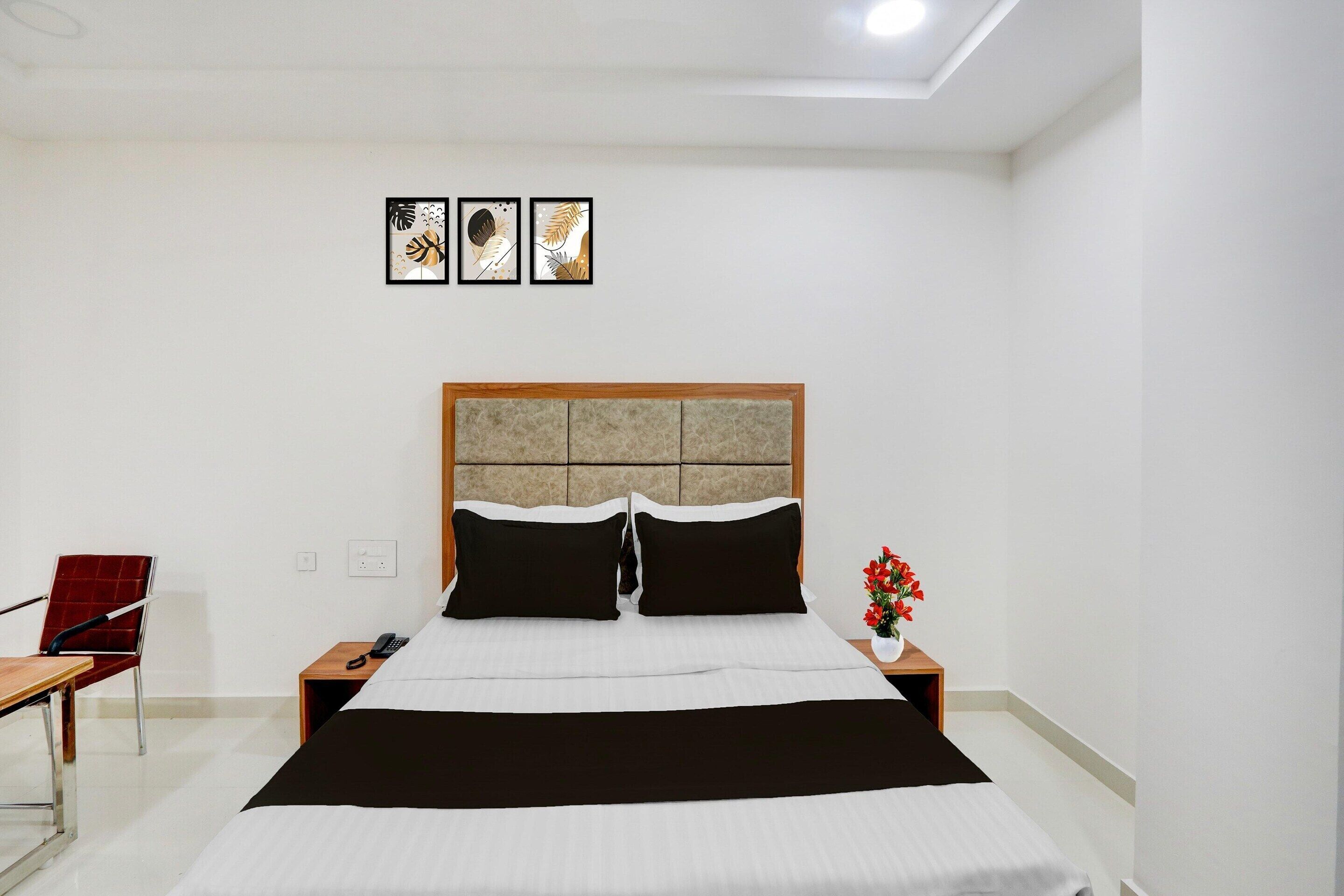 Ein Hotelzimmer mit Bett, Nachttisch, Sessel und einer Wand mit drei gerahmten Bildern.